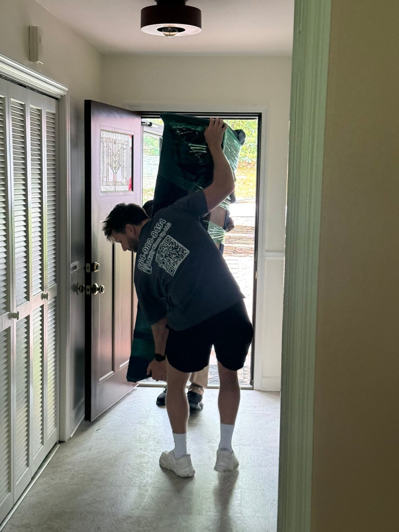 Southern Charm mover carrying wrapped furniture through a customer's front door