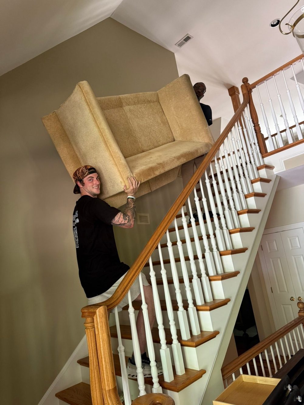 Two-man crew carrying a wrapped mattress out of a Greenville home