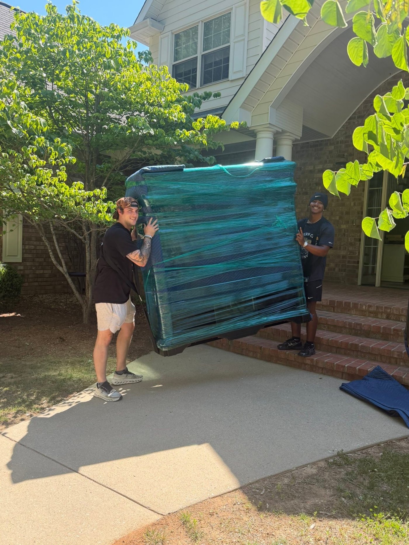 Crew wrapping and protecting a mattress before loading